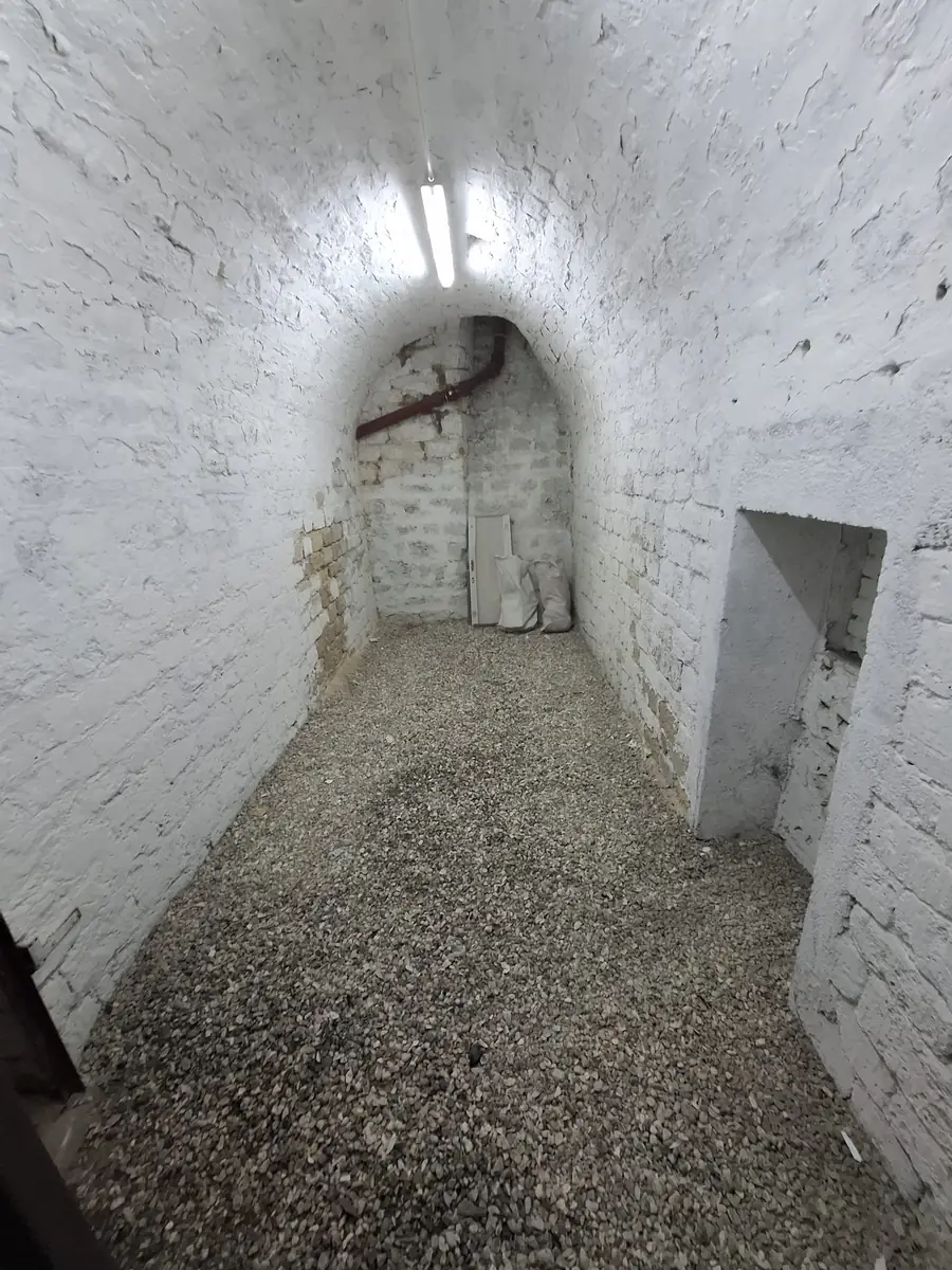 Murs chaulés, sol regravillonné — débarras de cave à Paris